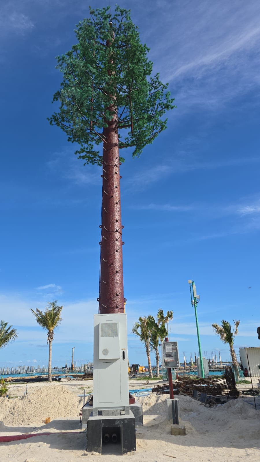 Pine-camouflaged tower with equipment cabinet on an island site