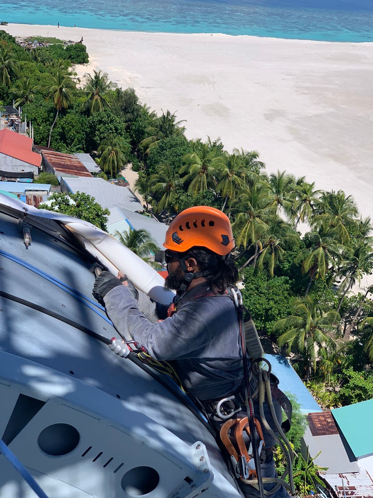 Rope-access technicians servicing a microwave dish over the lagoon