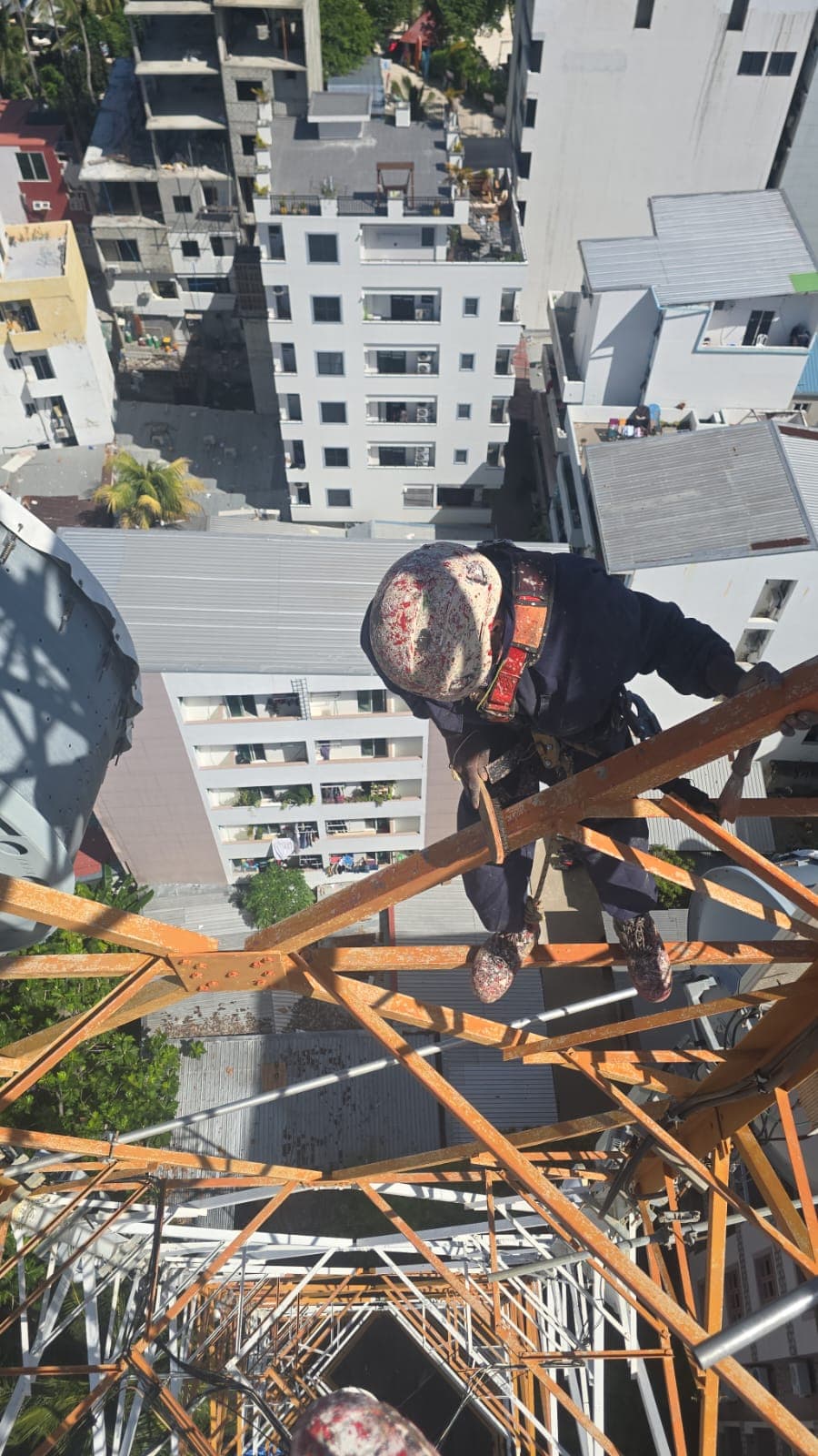 Rishthaa technician descending a tower above Malé rooftops