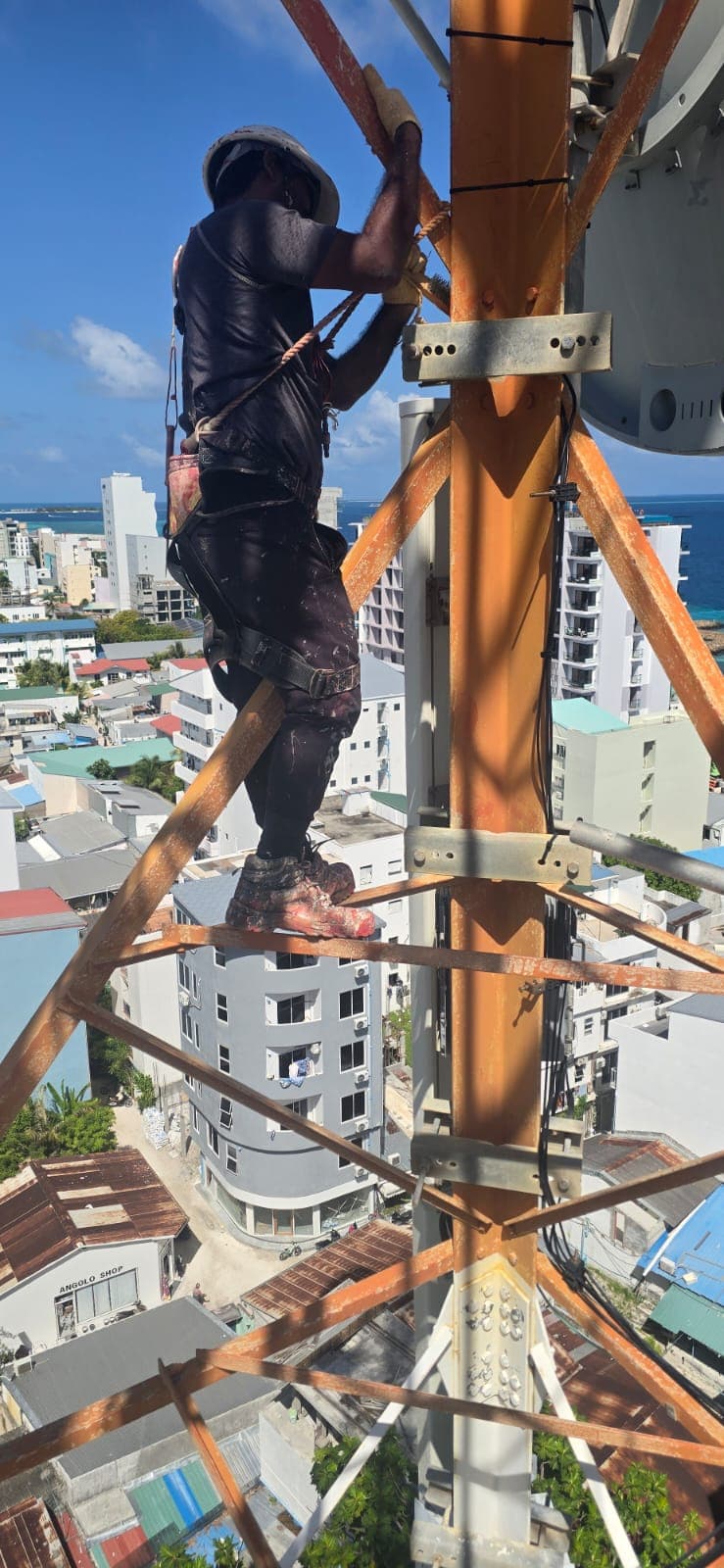 Tower technician securing equipment above the Malé skyline