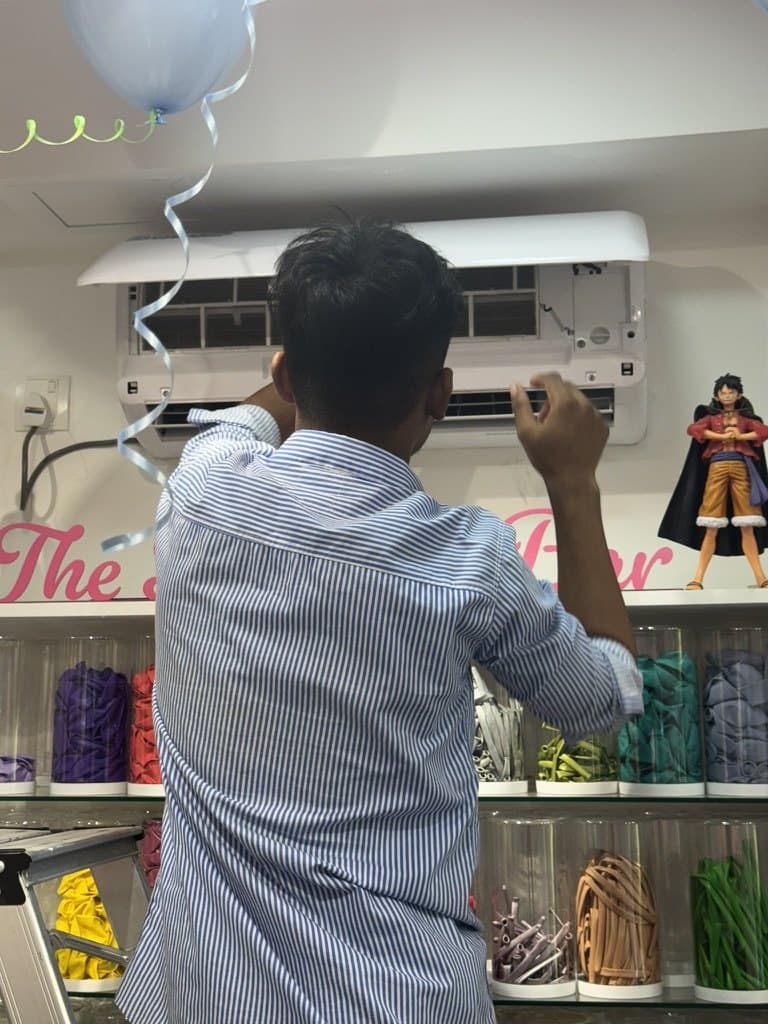 Rishthaa technician working on the front panel of a wall-mounted split AC indoor unit